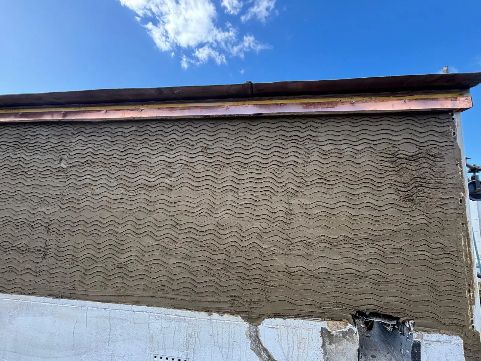 Scratch coat render applied to the outer face of the balcony wall
