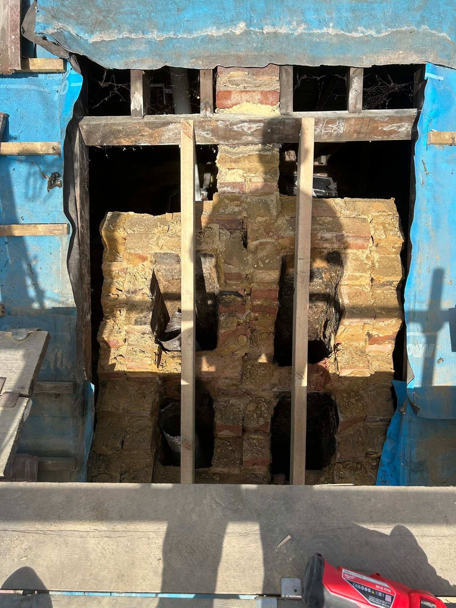 Scaffold erected and tiles stripped back on a Brighton property to expose the chimney stack at roof level — start of demolition works