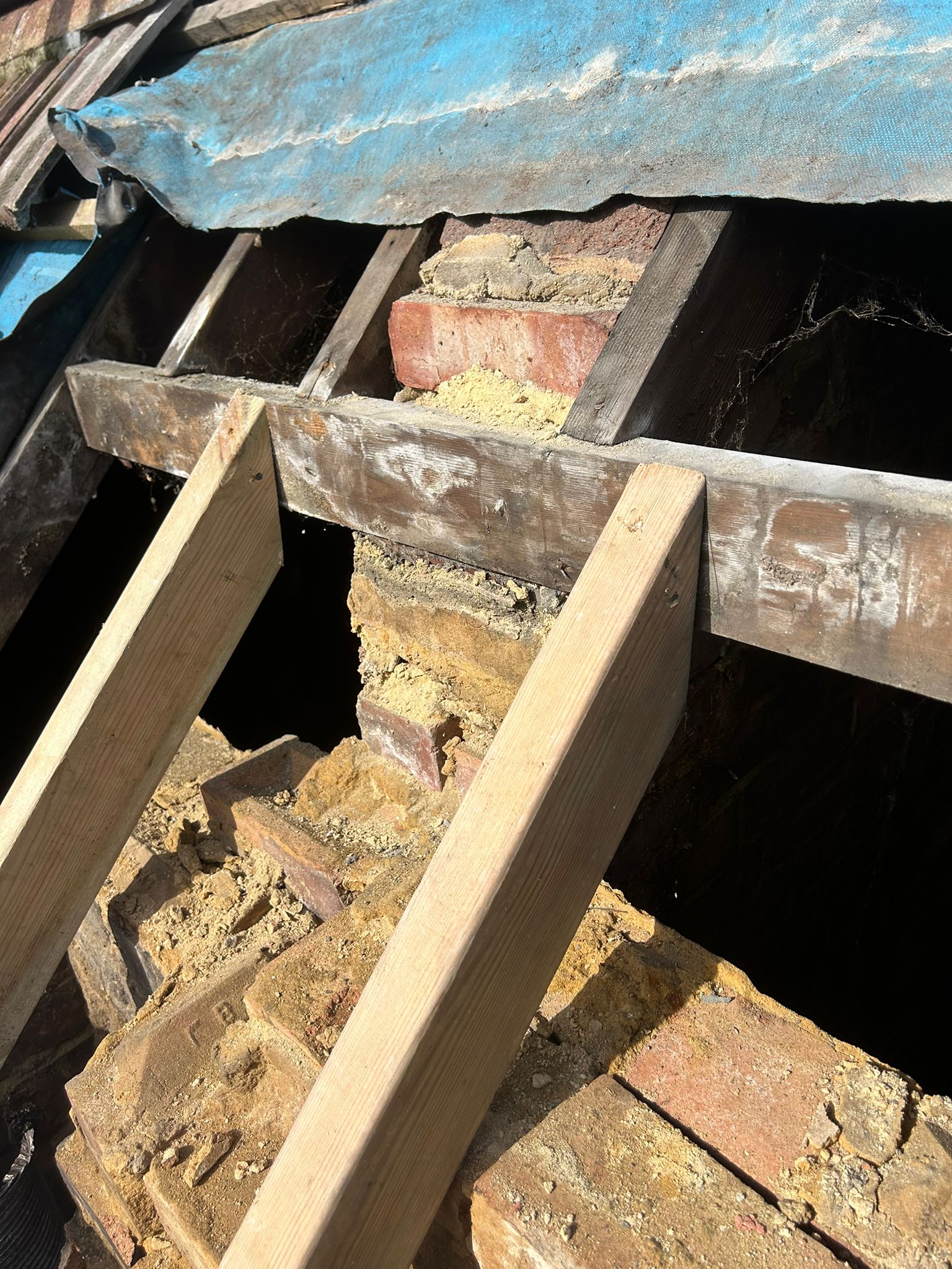 Flue liner exposed in the chimney void during demolition — void opened up fully across the width of the stack with new rafters positioned alongside