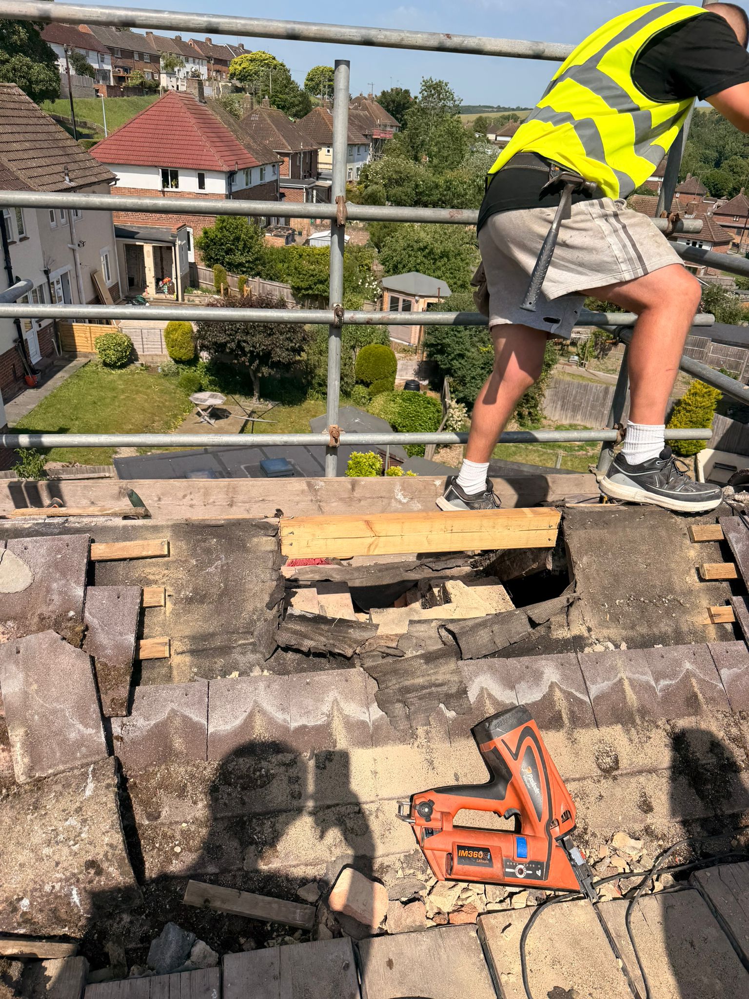Open roof void after chimney stack removal on a Bevendean property — old felt and battens stripped, nail gun on site and structural timbers being fitted
