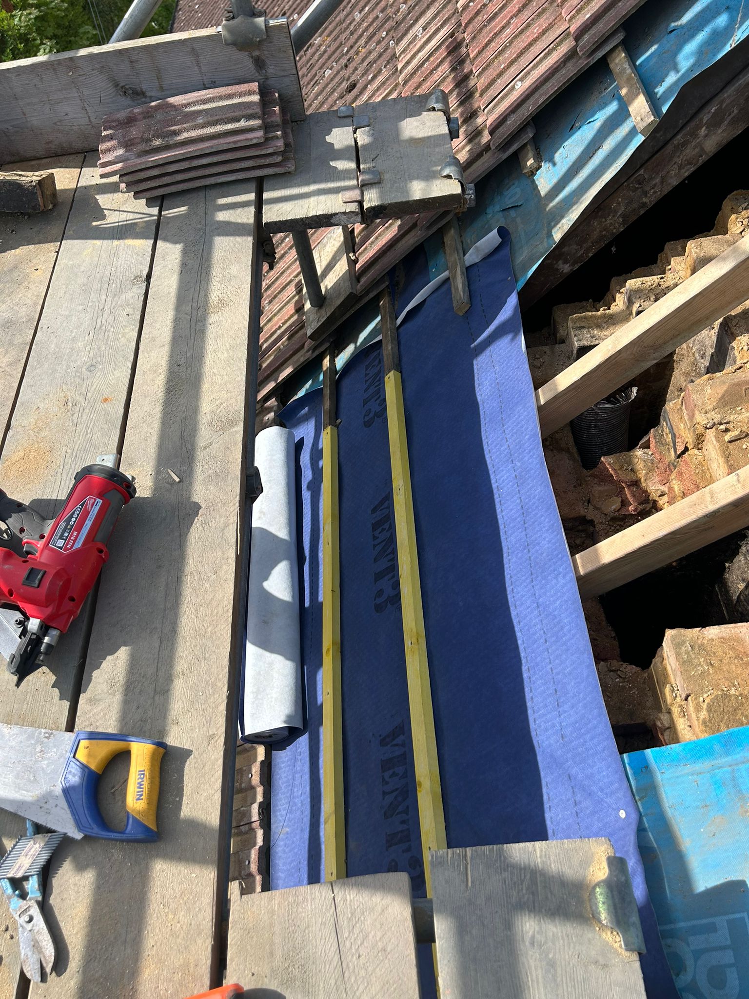 Breathable roofing felt and tiling battens being installed over the chimney void — felt lapped correctly into the existing felt runs either side