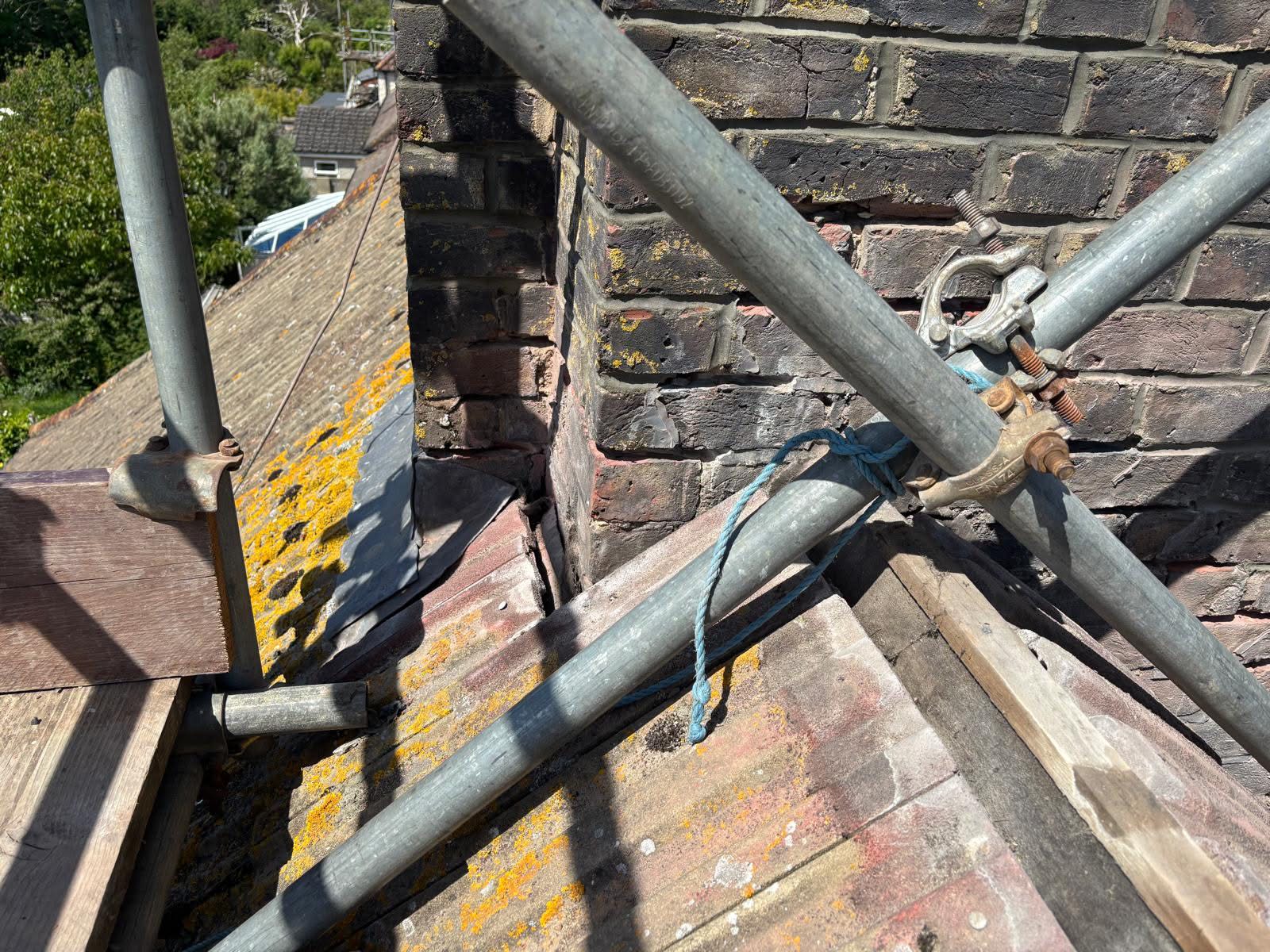 Corner detail of the repointed chimney stack in Portslade — fresh mortar joints to the corner and new lead step flashing being fitted at the roofline junction