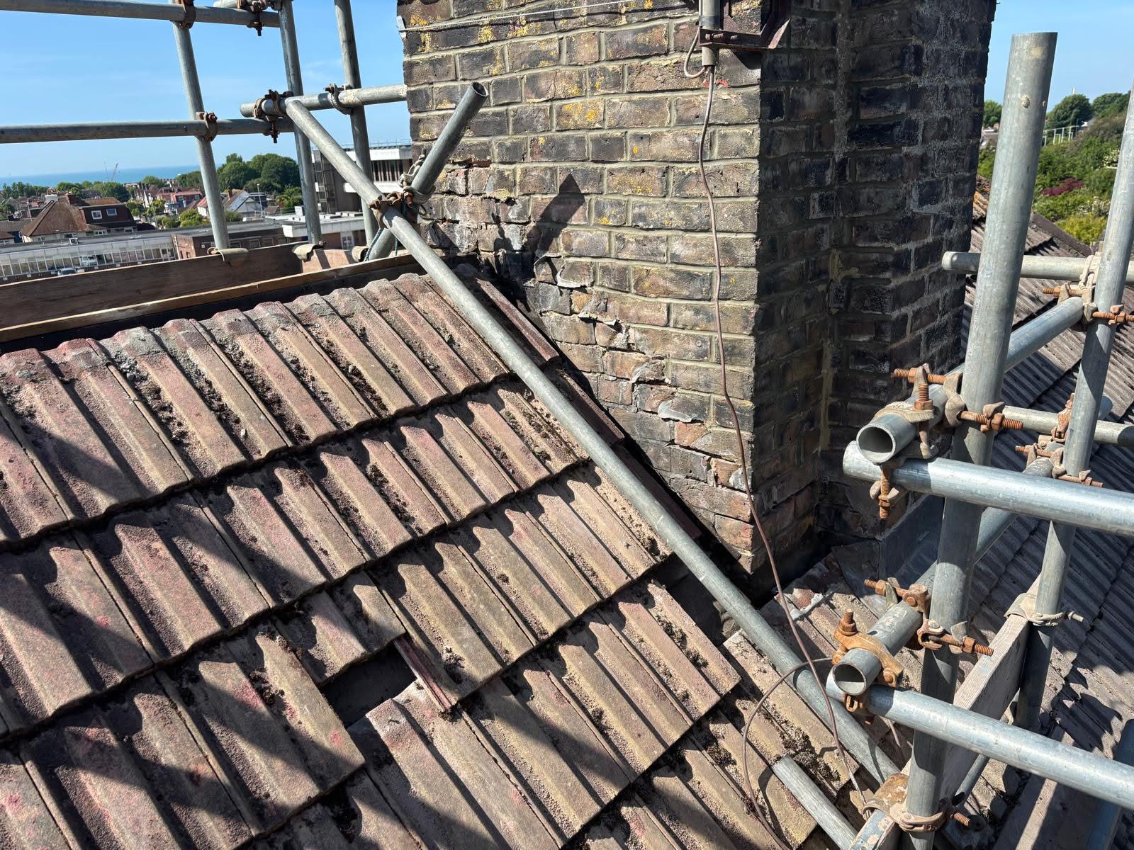 Old lead flashings stripped from the chimney base in Portslade — bare brickwork exposed at the junction with the roof tiles ready for new Code 4 lead installation