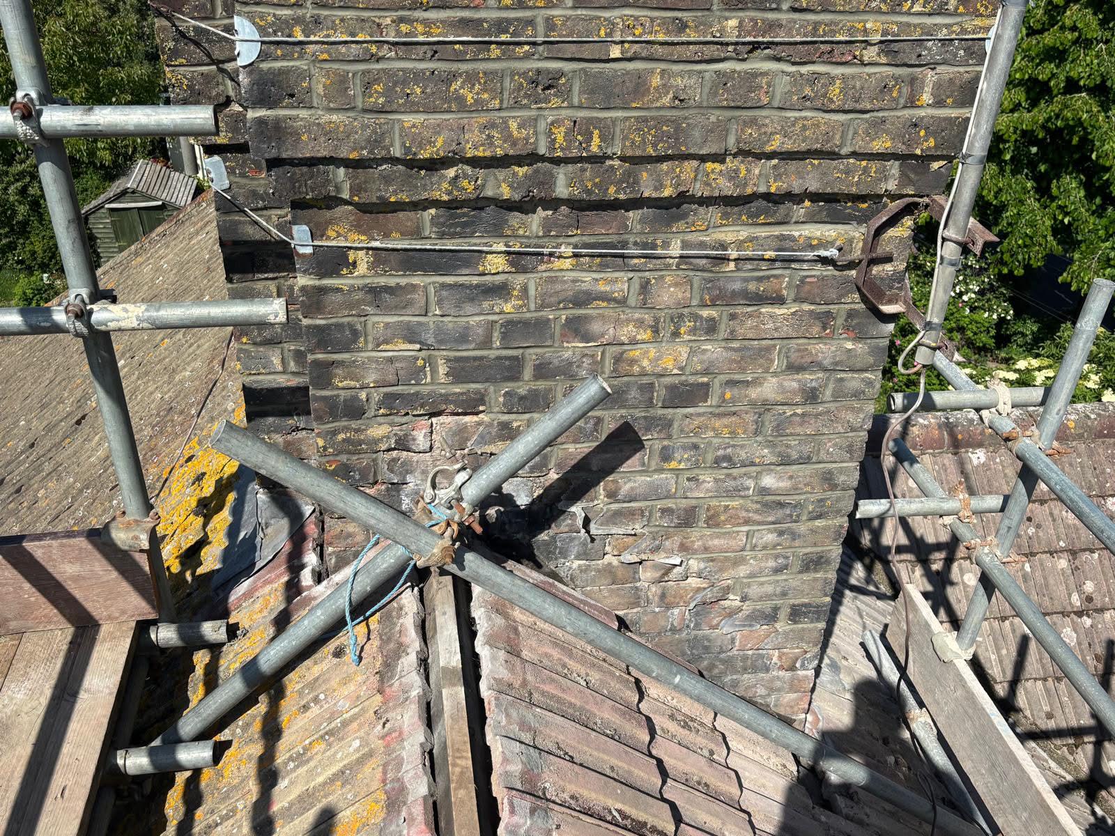 Chimney brickwork repointing complete on one face — fresh mortar joints throughout, scaffolding still in place on the Portslade property
