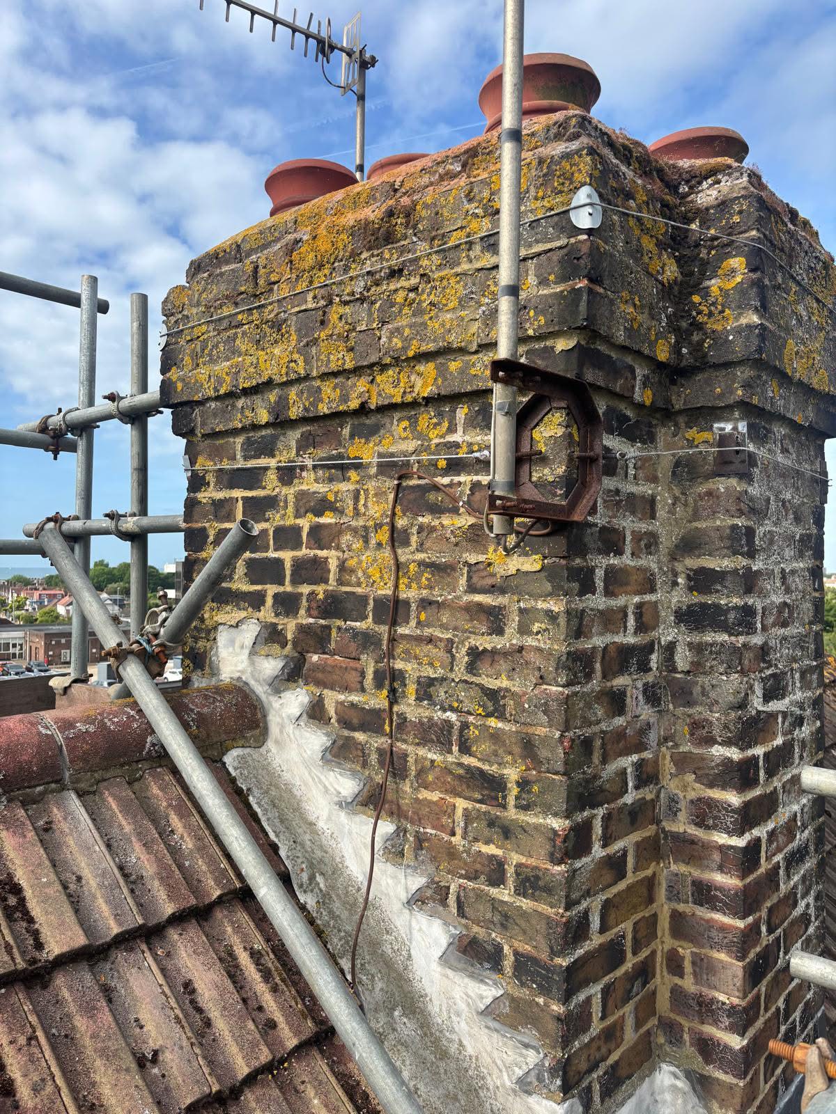 Side view of the chimney stack before repointing on a Portslade property — failed mortar joints and weathered brickwork visible across the full height of the stack