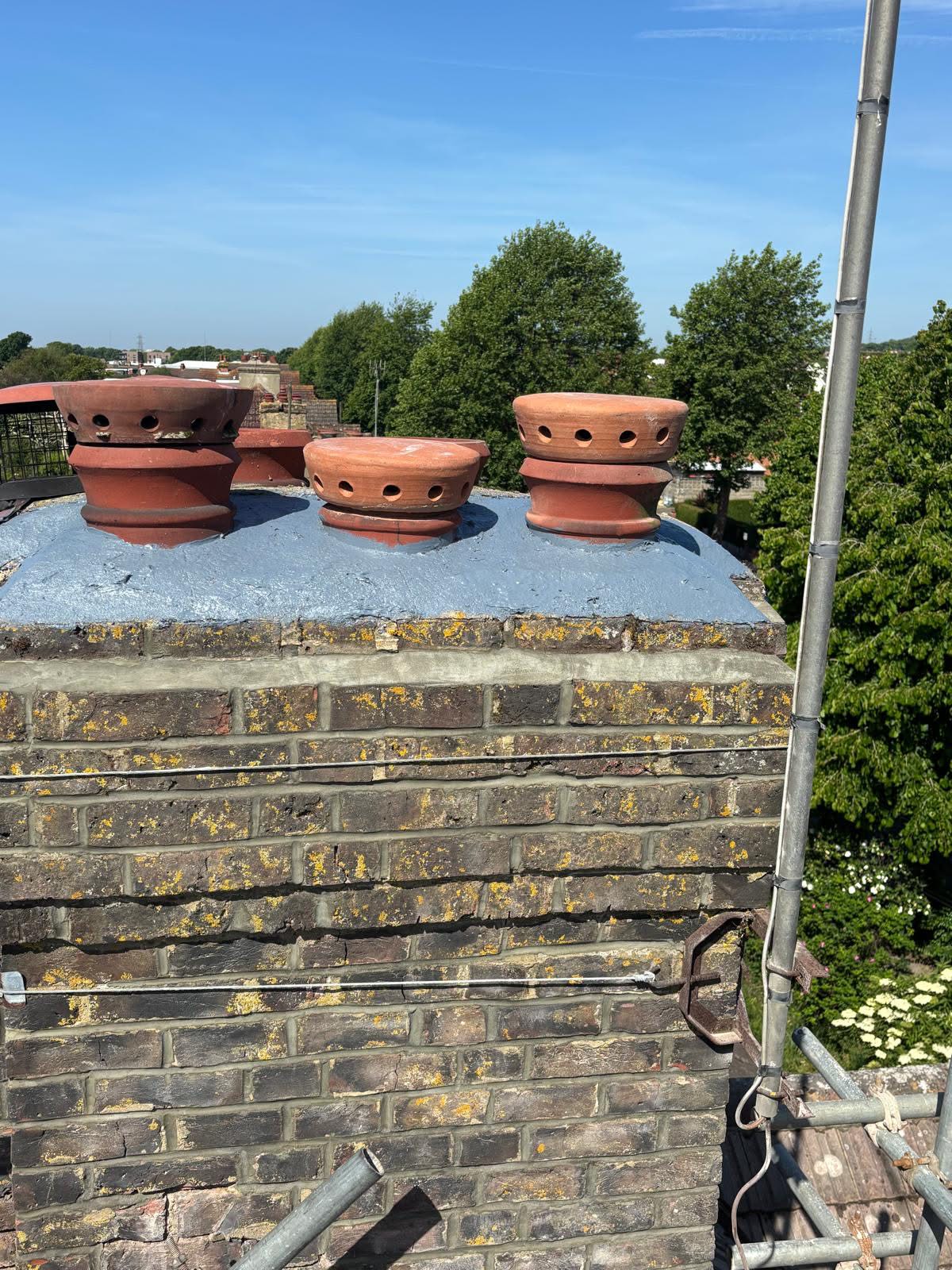 Aquapol waterproof sealant applied to the chimney top in Portslade — distinctive blue coating to the crown with three new flue ventilators fitted to the pots to prevent water ingress