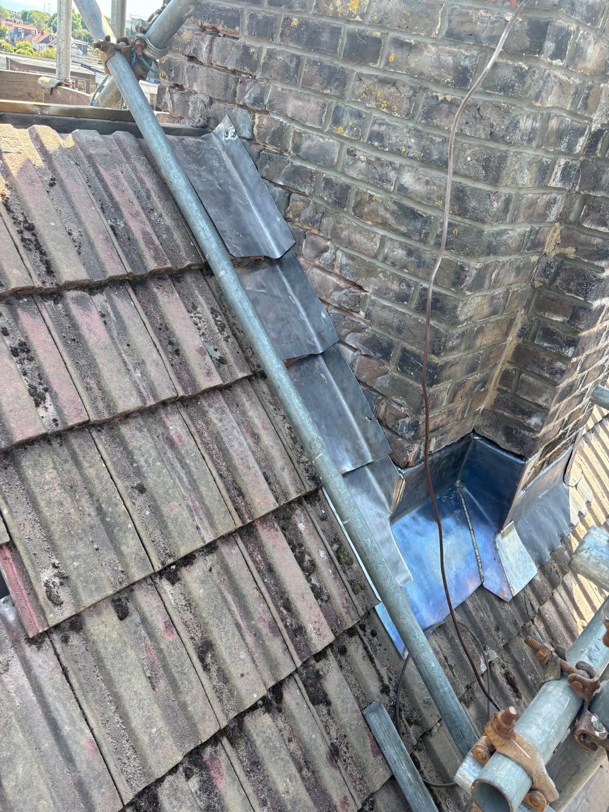 New Code 4 lead step flashings installed at the chimney base in Portslade — overlapping lead soakers and cover flashings dressed into the brick joints