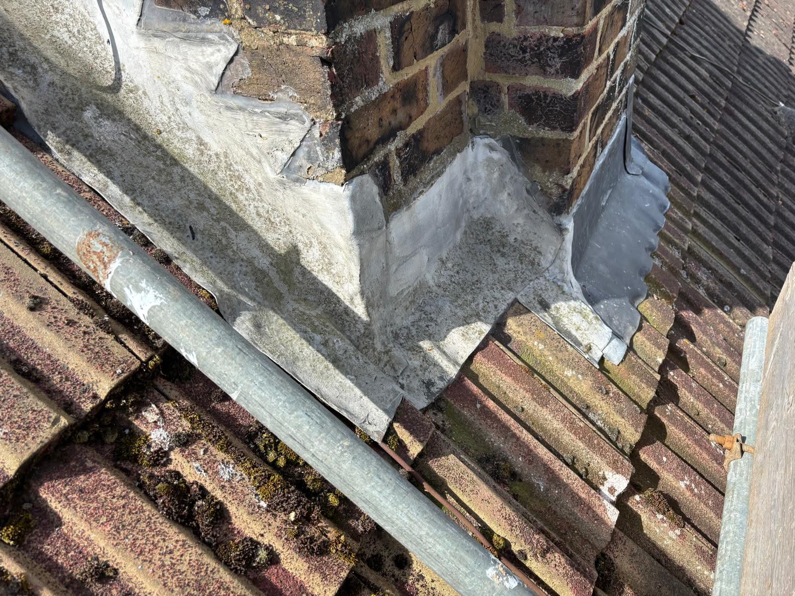 Old lead flashing at the base of the chimney stack showing severe deterioration — cracked, displaced and no longer weathertight