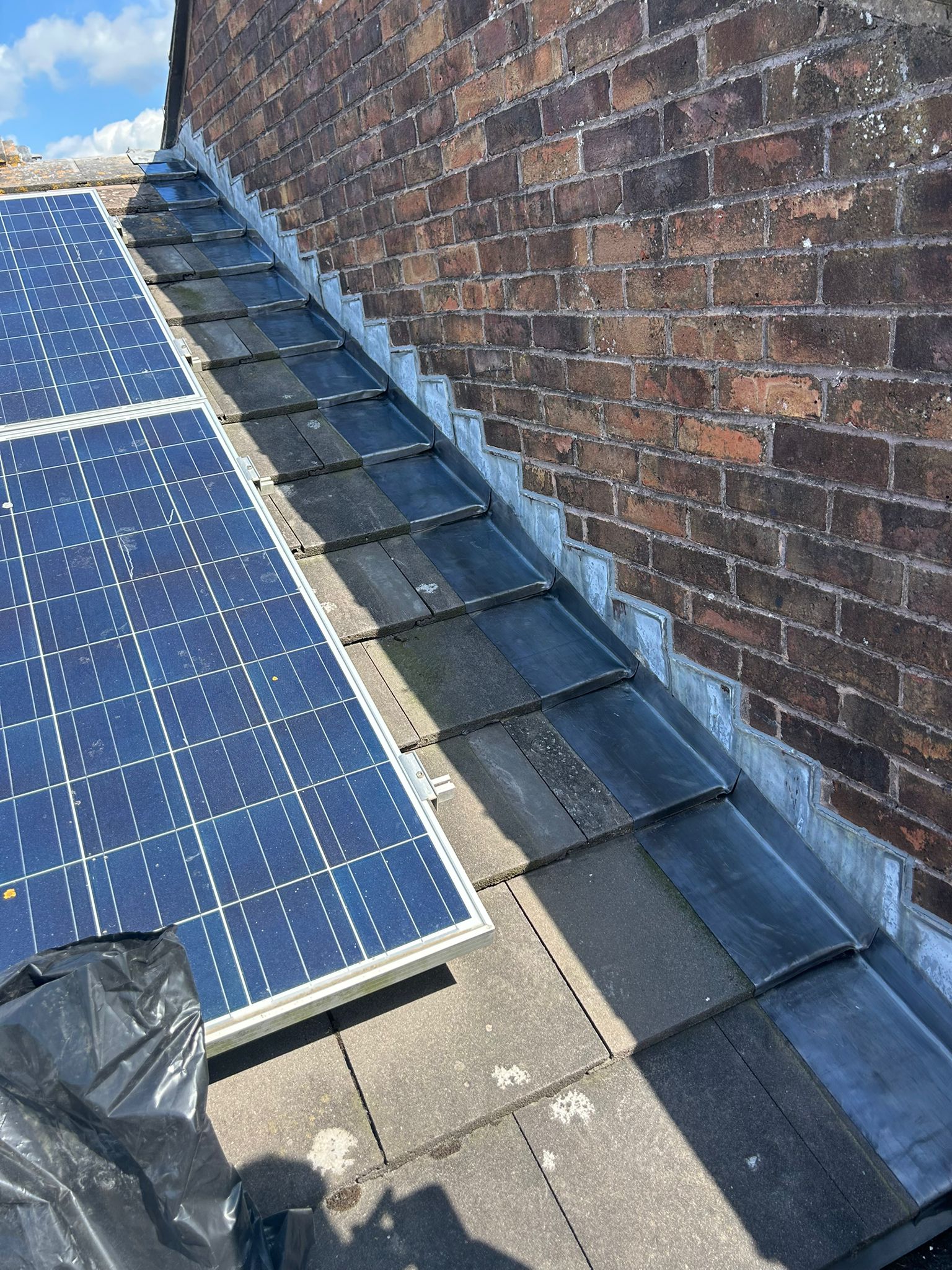 Finished lead soaker flashing and Stormdry treatment on a Whitehawk, Brighton property — roof-to-wall junction fully weathertight with solar panels reinstated