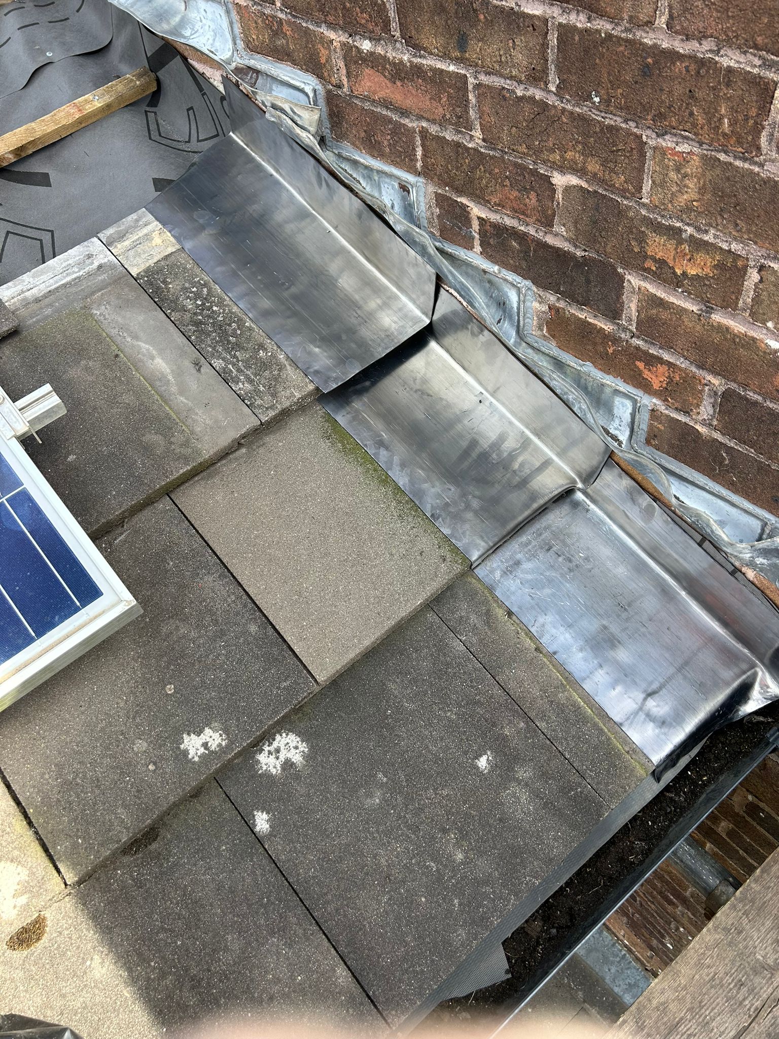 New lead soakers fitted across the full width of the roof abutment in Whitehawk, Brighton — each soaker dressed between the tiles and up the face of the adjoining wall