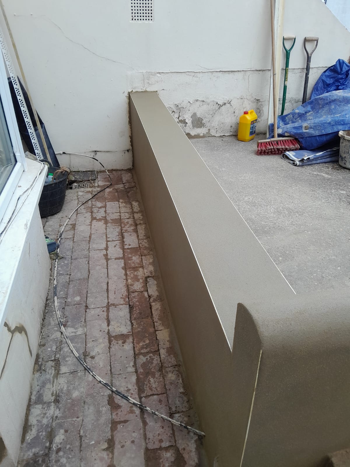 Freshly rendered boundary wall — smooth finish applied over rebuilt brickwork, Brighton